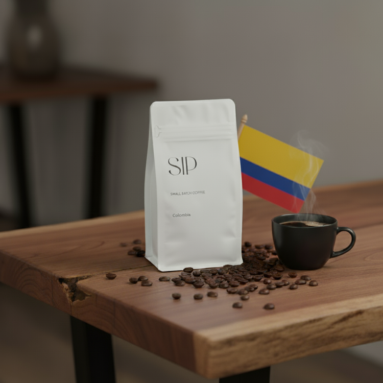 Coffee bag, cup, and beans on a wooden table with a Colombian flag in the background