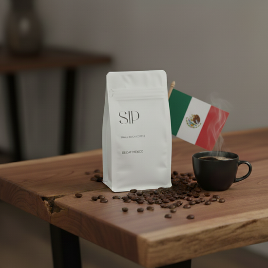 Coffee bag with 'SIP' branding, coffee beans, and a steaming cup on a wooden table with a Mexican flag in the background.