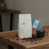 Coffee bag with 'SIP' branding, coffee beans, and a steaming cup on a wooden table.